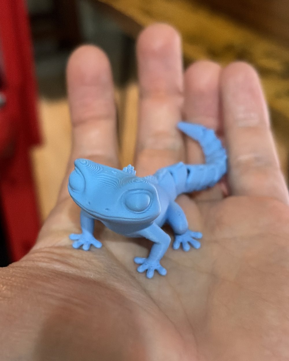 A small bright blue articulated gecko resting in an open palm