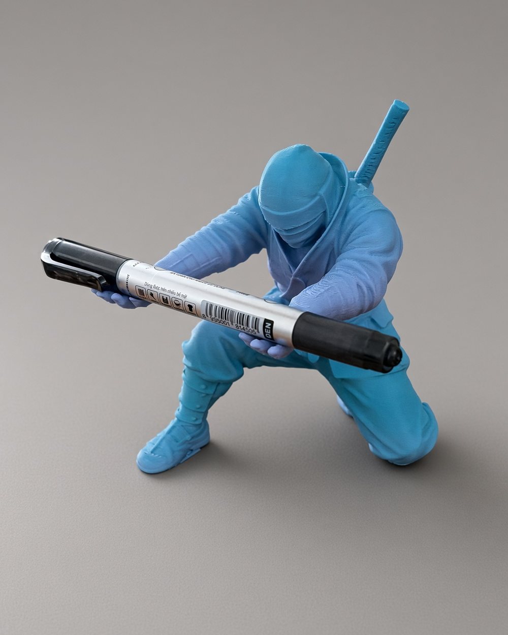 A blue ninja figure holding a pen across its outstretched arms