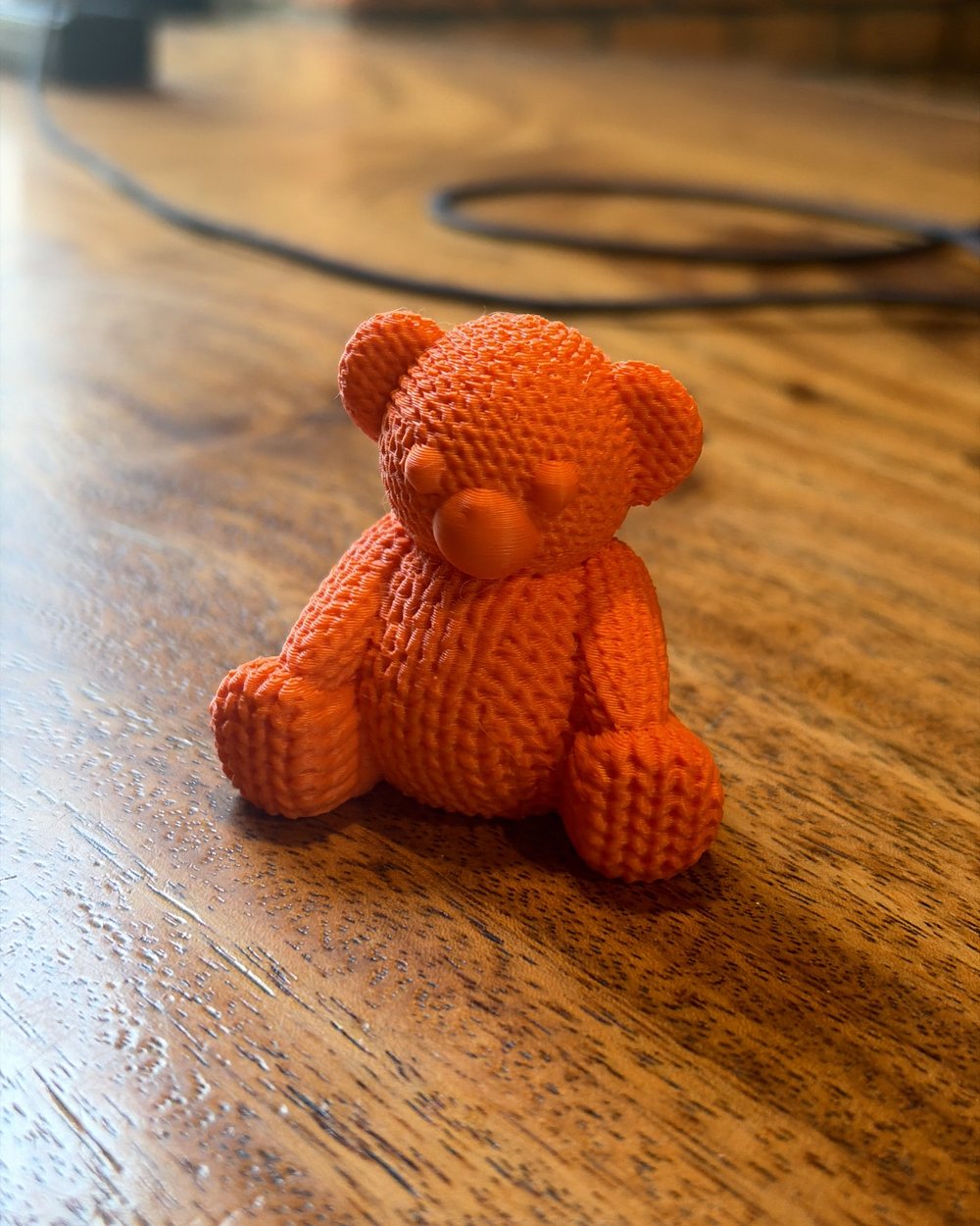 A small orange teddy bear printed with a knitted-wool texture