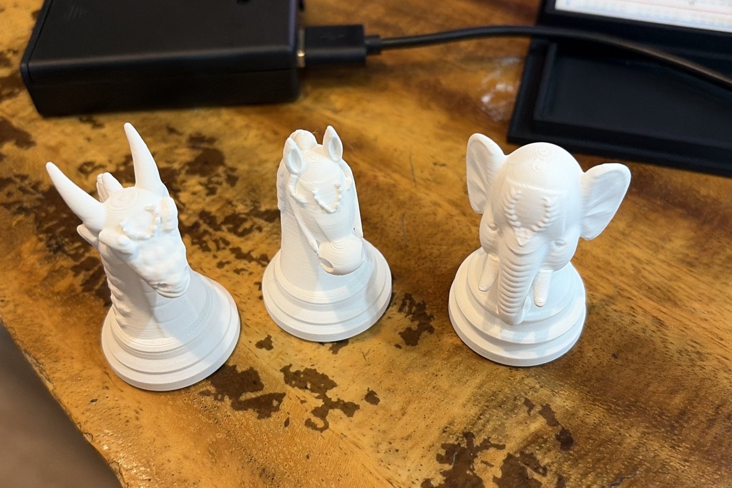 Three printed white pieces close up: a dragon-head knight, a horse and an elephant